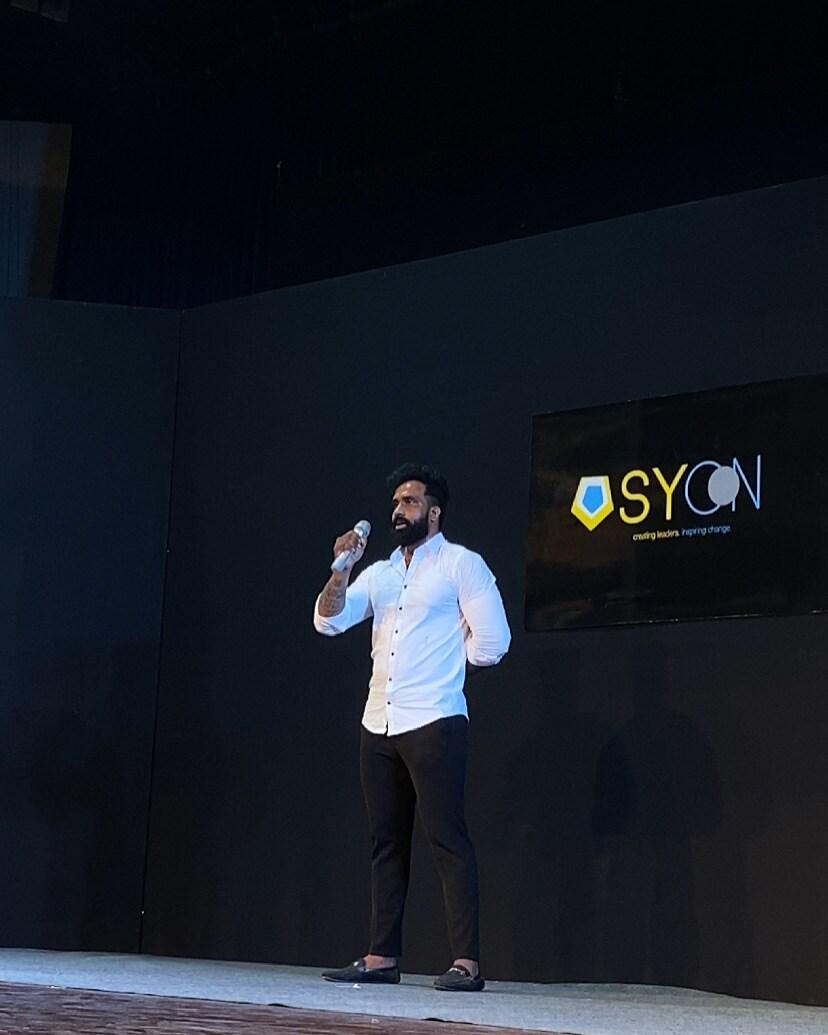 Naresh Kumar speaking on stage at a SYCON event